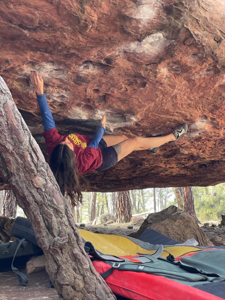 Lucie en bloc sous un surplomb rocheux, en forêt